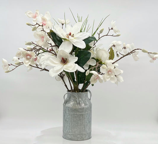 Magnolias blancas y ramitas de plantas de dinero en jarra de leche