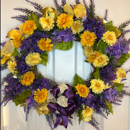Corona de 14" con lilas moradas, crisantemos amarillos y dorados, lazo marfil